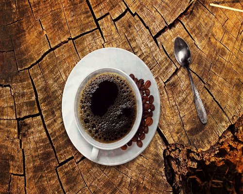 A glass of water next to a morning cup of coffee on a table
